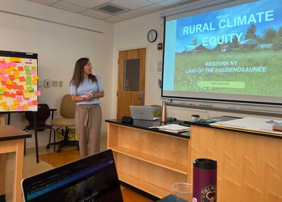 Presenter speaking in a classroom beside a slide titled “Rural Climate Equity.”