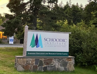 Sign for Schoodic Institute at Acadia National Park at sunset with trees behind.