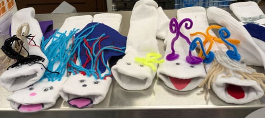 Handmade sock puppets decorated with yarn, pipe cleaners, and craft materials.